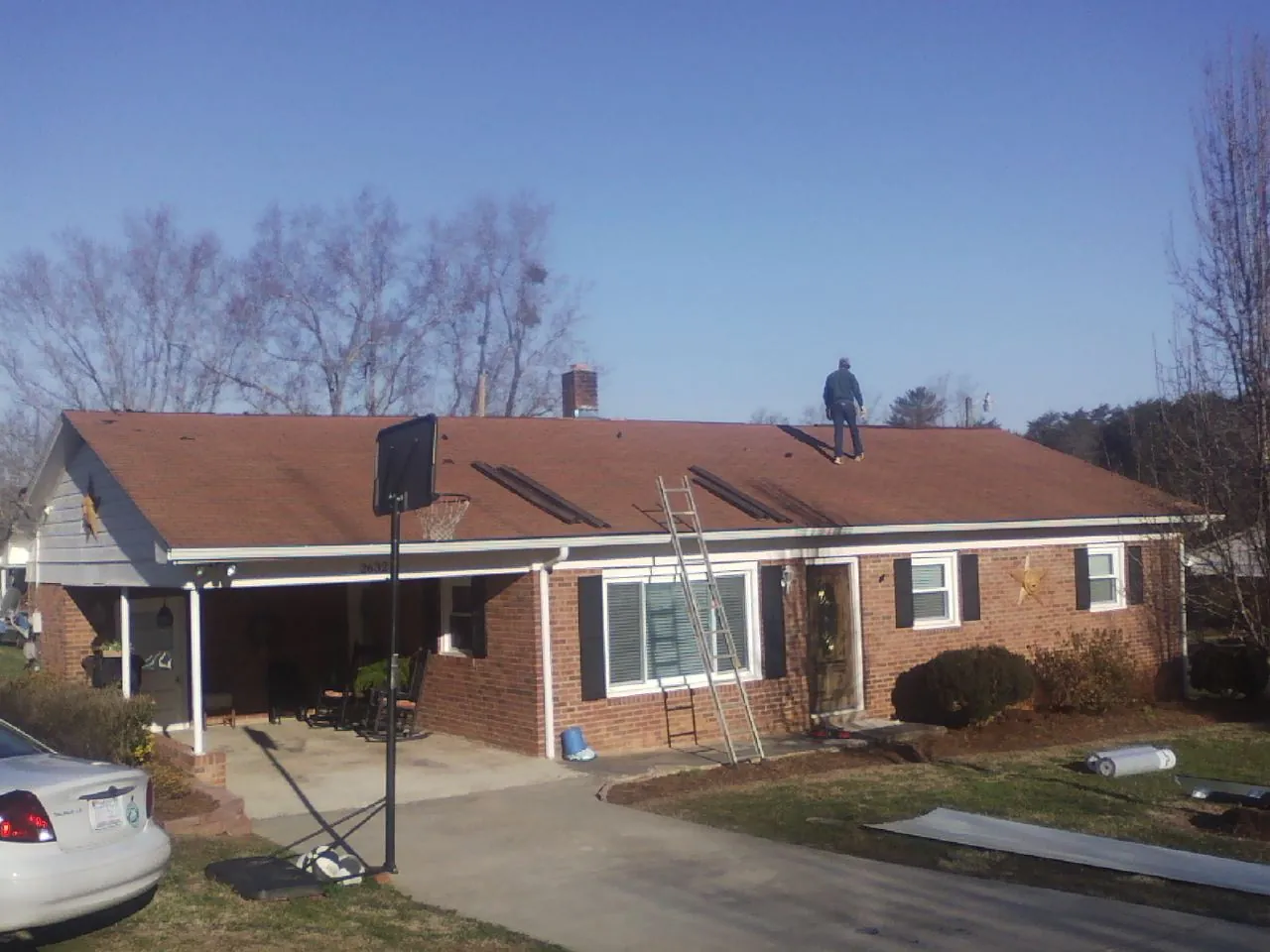 Roofer stripping a shingle roof on a brick ranch before metal panels in Culdesac