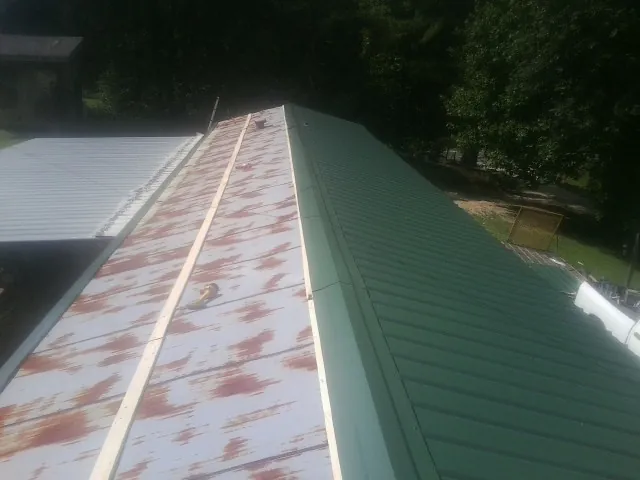 Old rusted panels beside newly installed green metal roofing — Wind Damage Roof Repair by Roofing Brothers in Culdesac