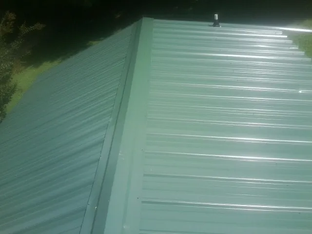 New green metal panels meeting at the ridge of a roof — Flat Roof Repair work by our crew in Culdesac