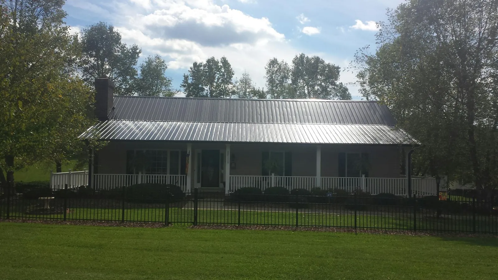 Gray metal roof on a brick ranch with a full width front porch — Gutter Guard Installation work by our crew in Culdesac